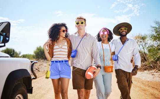 Friends walking together on a sunny day near a safari vehicle, enjoying a group adventure.
