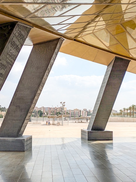 Grand Egyptian Museum entrance with engraved pillars and city view.