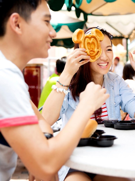 People enjoying Mickey Mouse-shaped waffles at Disneyland Hong Kong.