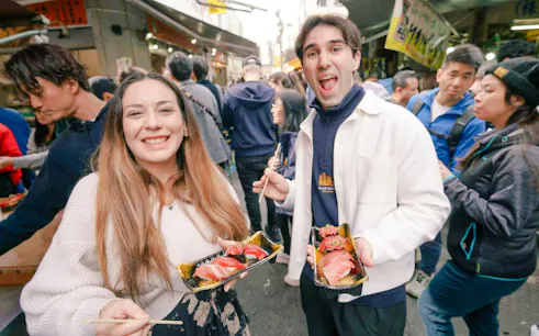 Tourists sampling sushi at Tsukiji Fish Market in Tokyo.