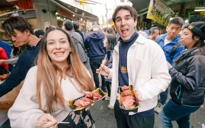 Tourists sampling sushi at Tsukiji Fish Market in Tokyo.