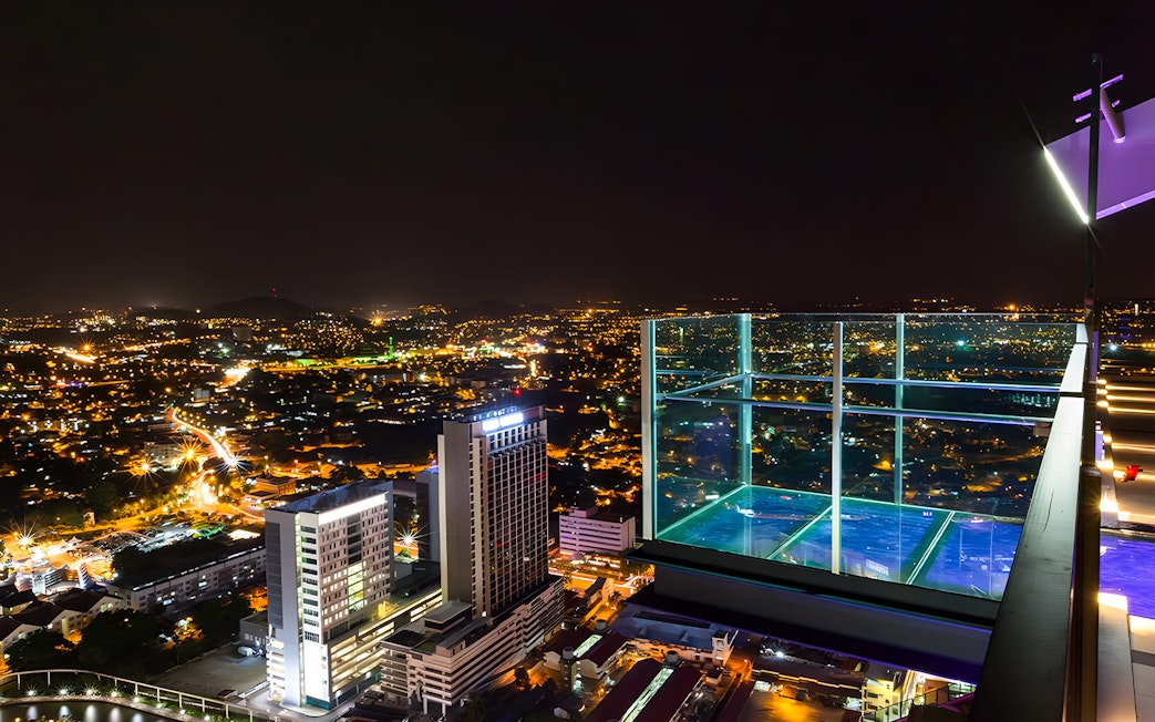 Sky deck view from The Shore Sky Tower at night, overlooking city lights in Melaka, Malaysia.