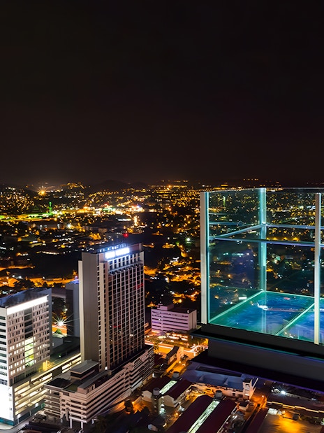 Sky deck view from The Shore Sky Tower at night, overlooking city lights in Melaka, Malaysia.