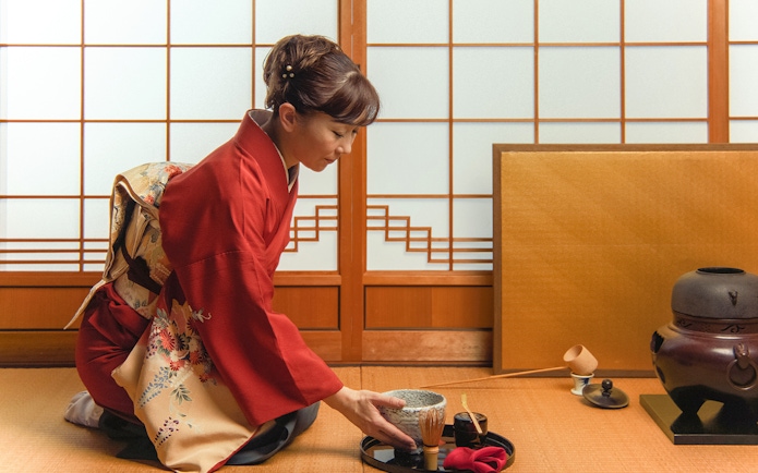Woman in kimono preparing matcha tea during Mt Fuji day trip experience.