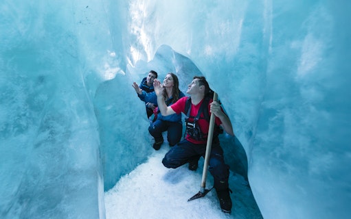 People exploring an ice cave during a glacier hike.