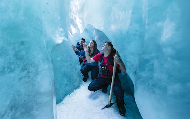 People exploring an ice cave during a glacier hike.