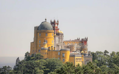 Pena Palace in Sintra, Portugal, viewed from a distance with surrounding greenery.