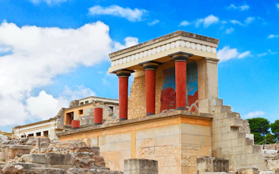 Knossos Palace ruins with red columns and fresco in Crete, Greece.