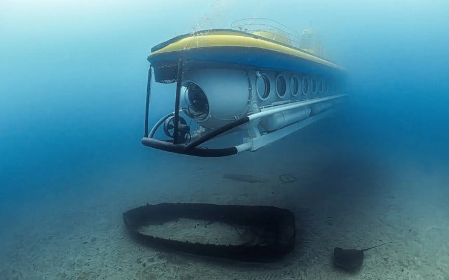 Submarine exploring underwater near shipwreck in Tenerife.