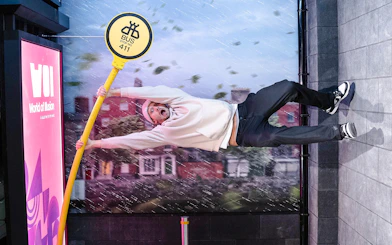 Guest clinging to a tilted bus stop sign at World of Illusions, creating a gravity-defying effect.