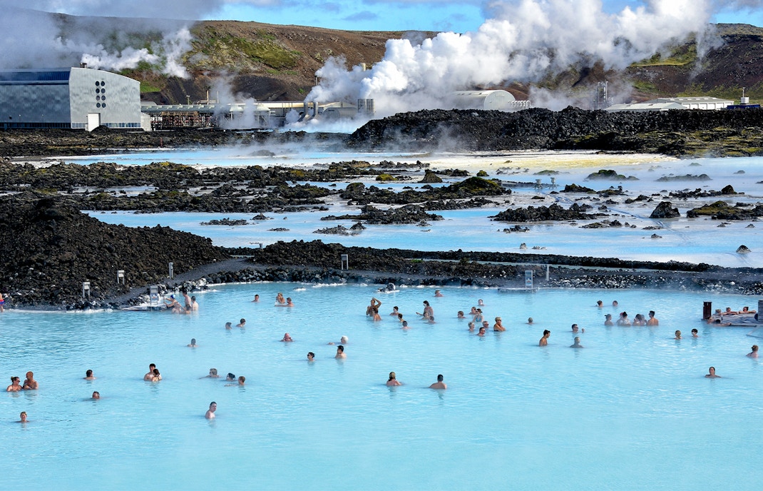 Bathers in Blue Lagoon hot springs with Svartsengi Geo-Thermal Plant in the background, Iceland.