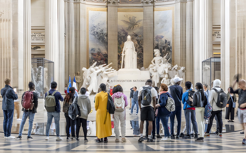Visitors observing statues inside the Paris Pantheon.