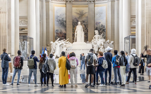 Visitors observing statues inside the Paris Pantheon.