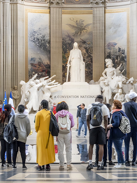 Visitors observing statues inside the Paris Pantheon.