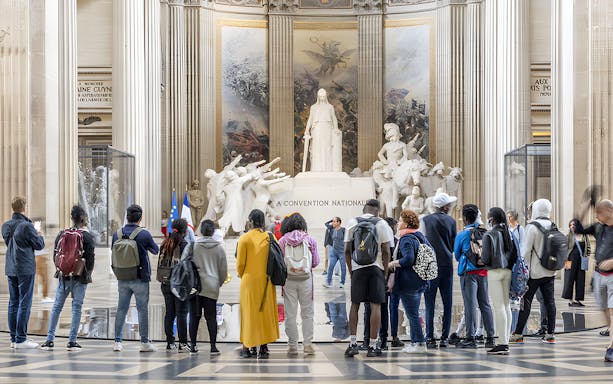 Visitors observing statues inside the Paris Pantheon.