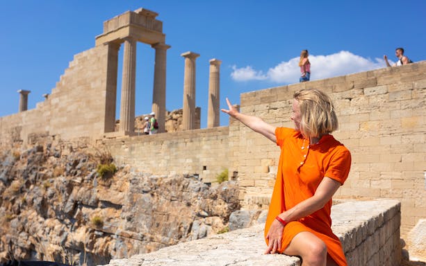 Woman pointing at the Parthenon on the Acropolis of Athens, Greece.