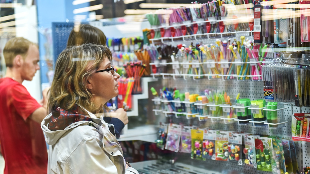 Young woman browsing stationery items in a store aisle.