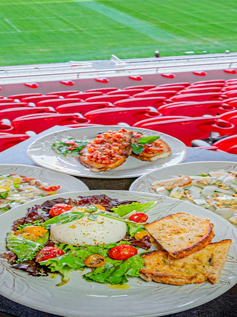 Plates of food at a restaurant overlooking Benfica Stadium's field.