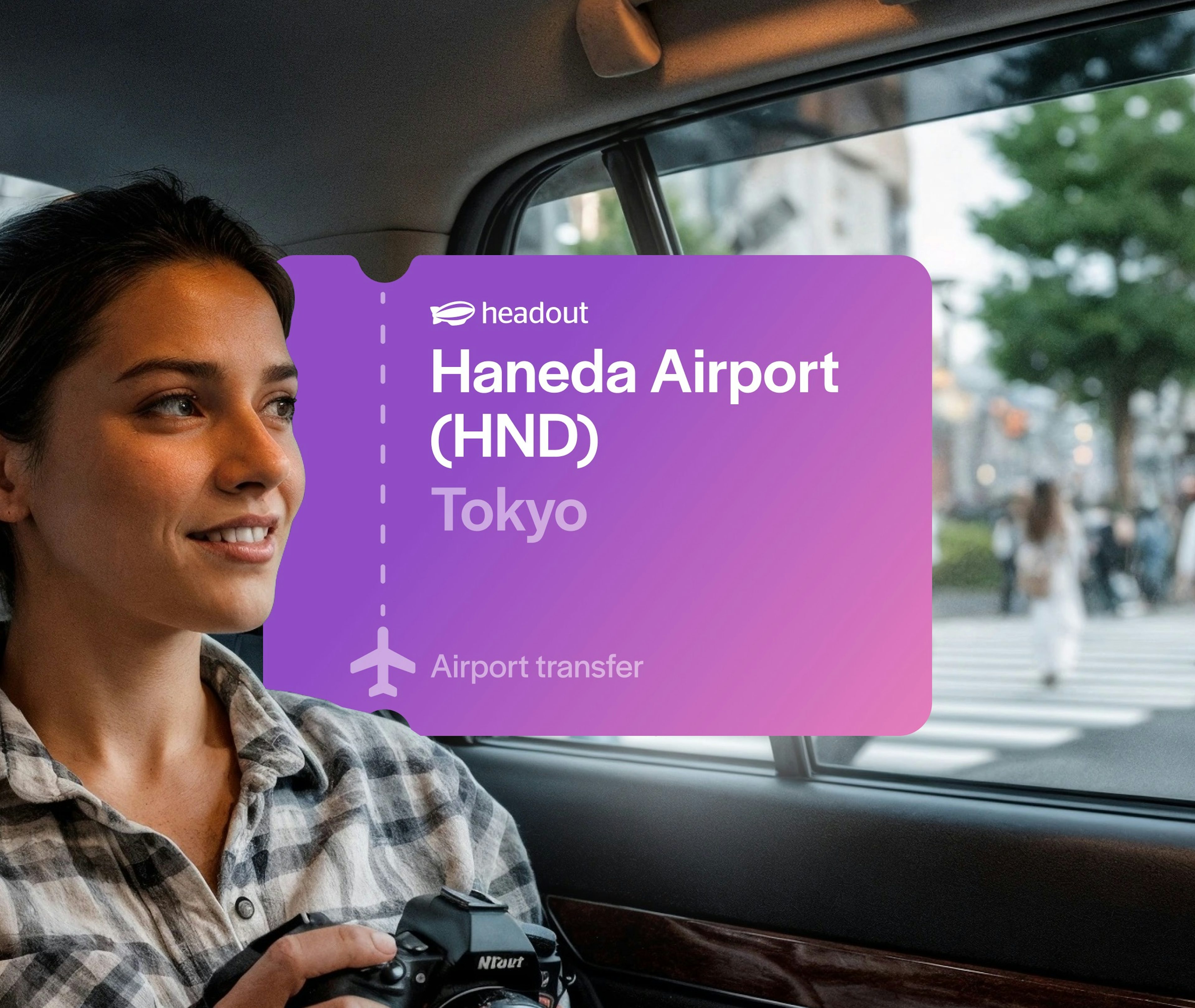 Woman holding camera in car passing through Shibuya, Tokyo with Haneda Airport transfer sign.
