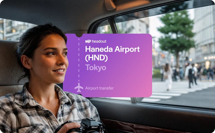 Woman holding camera in car passing through Shibuya, Tokyo with Haneda Airport transfer sign.