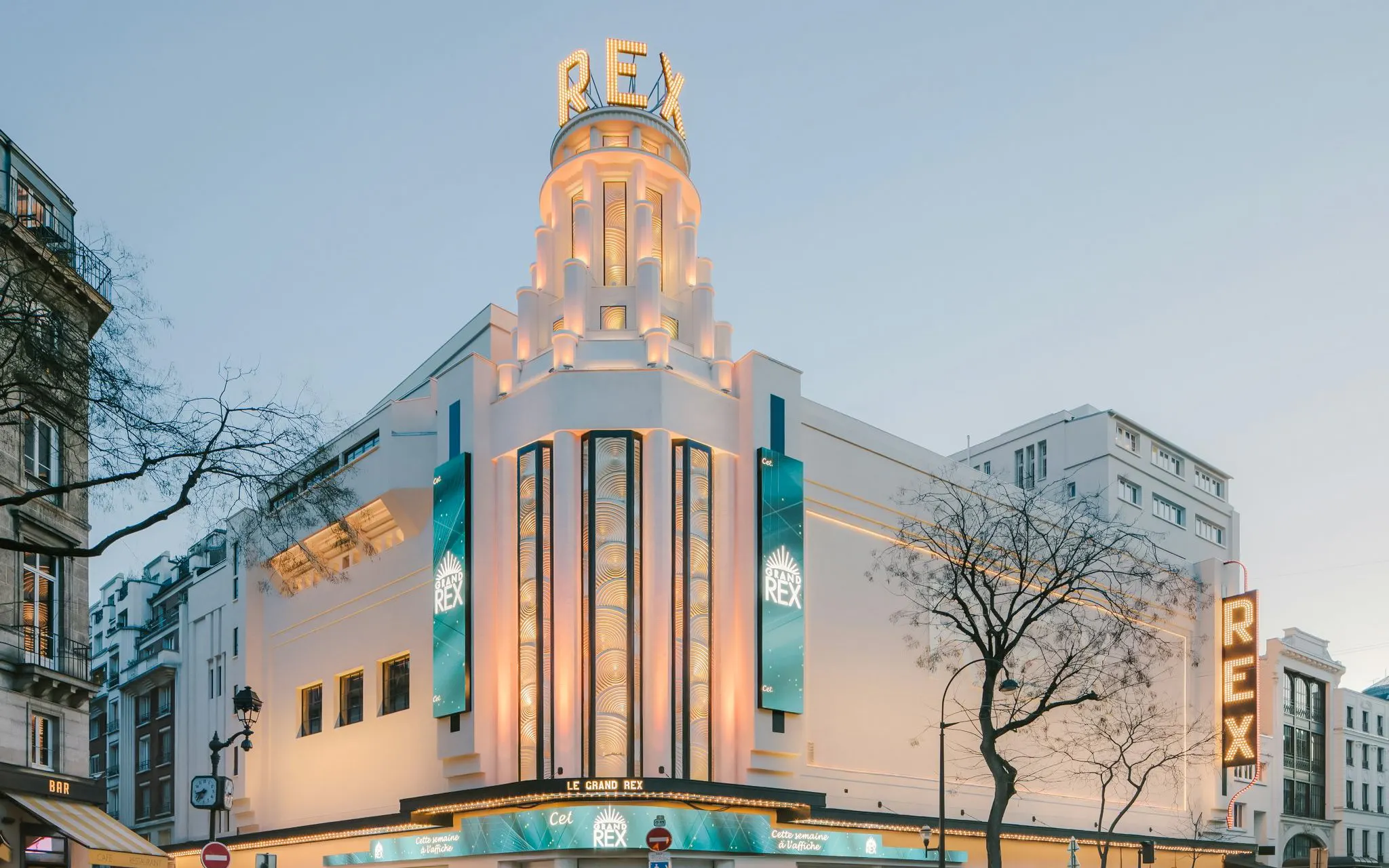 Le Grand Rex cinema facade in Paris with illuminated signs and art deco architecture.