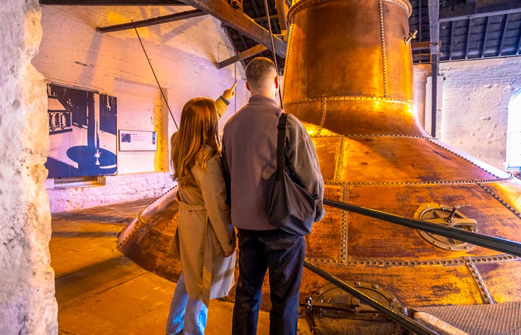 Midleton Distillery tour guide explaining whiskey production process with barrels in background.