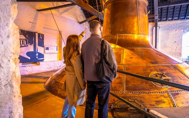 Midleton Distillery tour guide explaining whiskey production process with barrels in background.