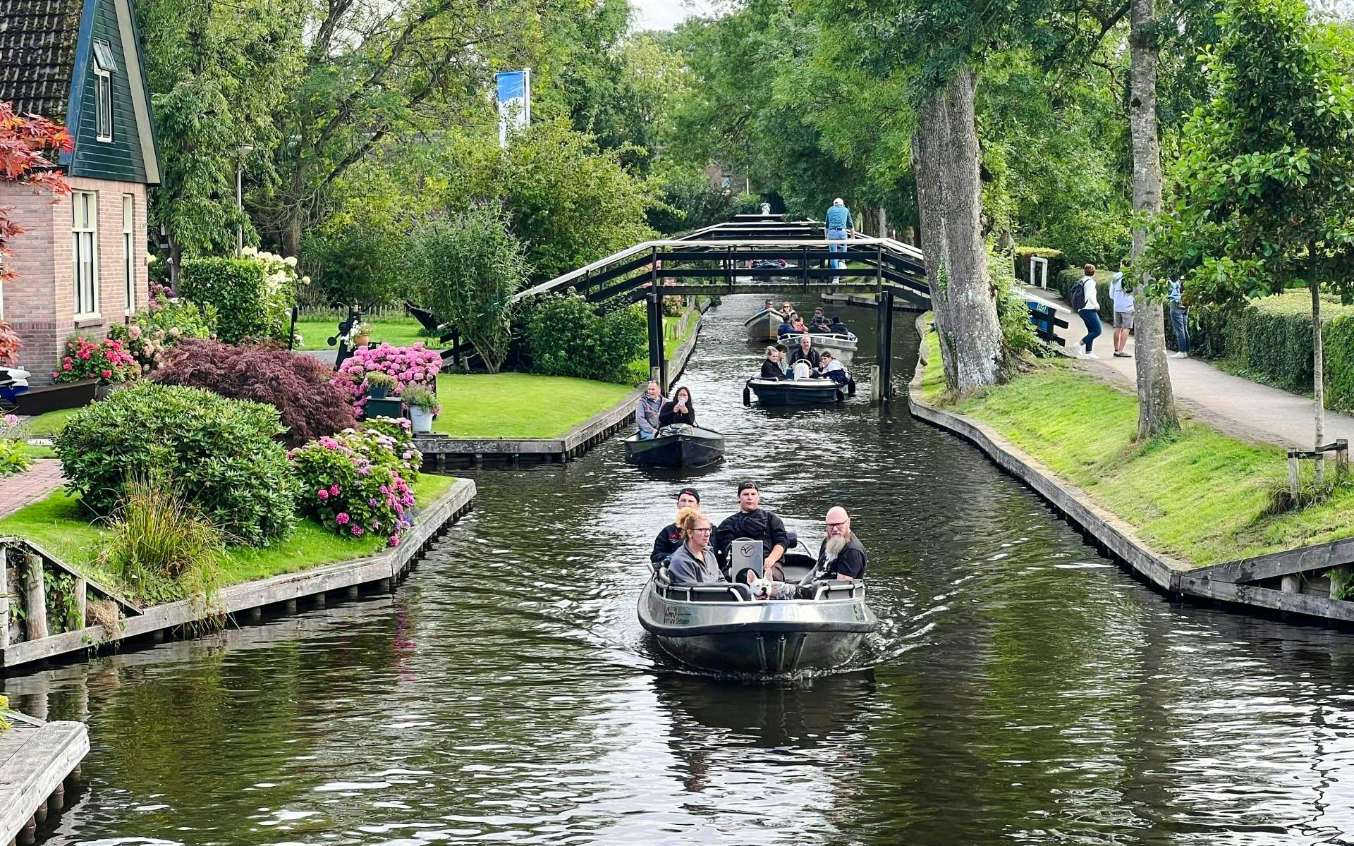 Boats navigating a canal in Giethoorn, surrounded by lush greenery and traditional Dutch houses.