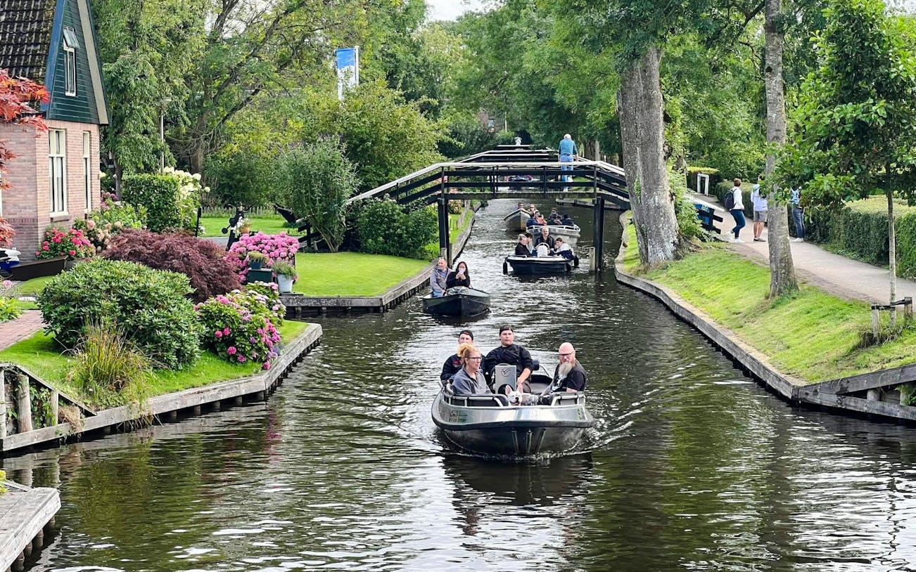 Boats navigating a canal in Giethoorn, surrounded by lush greenery and traditional Dutch houses.