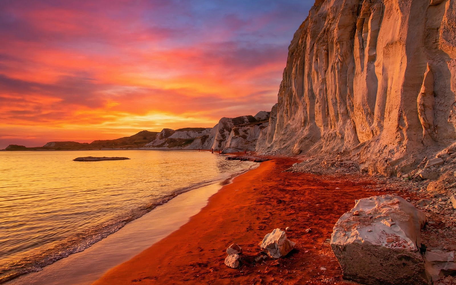 Sunset over red sand and cliffs at Xi Beach, Kefalonia Island, Greece.