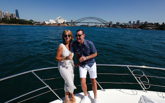 Couple enjoying Sydney Harbour cruise with views of Opera House and Harbour Bridge.