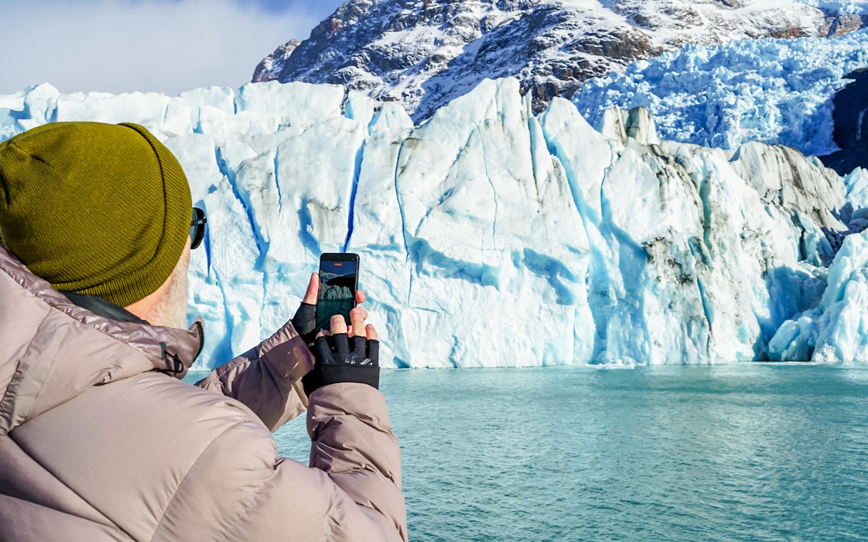 Tourist photographing Perito Moreno Glacier from a cruise boat in Argentina.