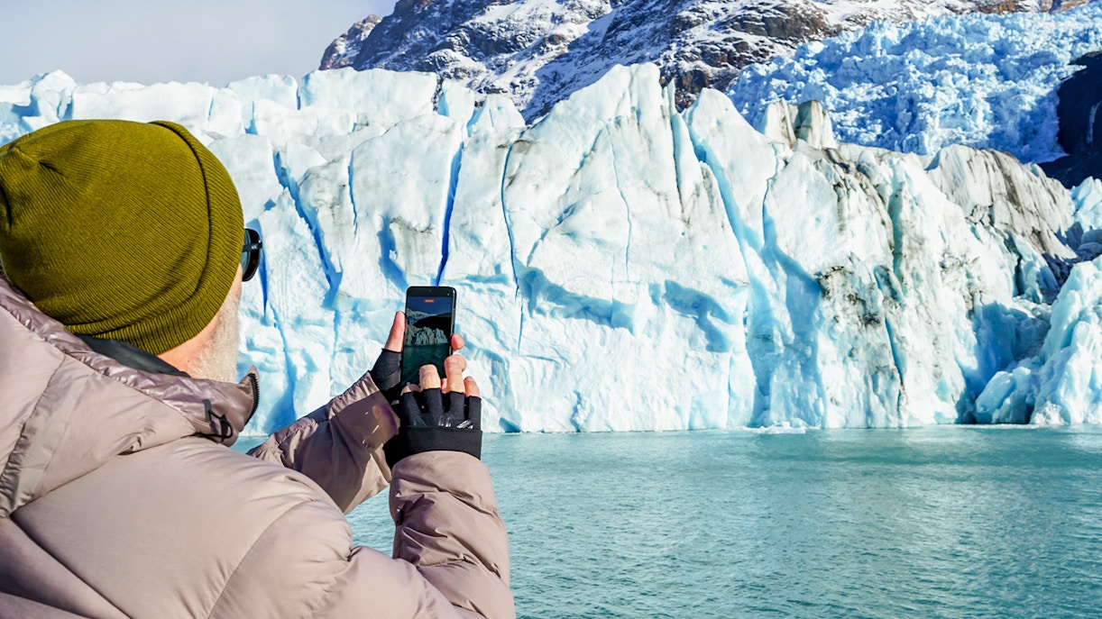 Tourist photographing Perito Moreno Glacier from a cruise boat in Argentina.