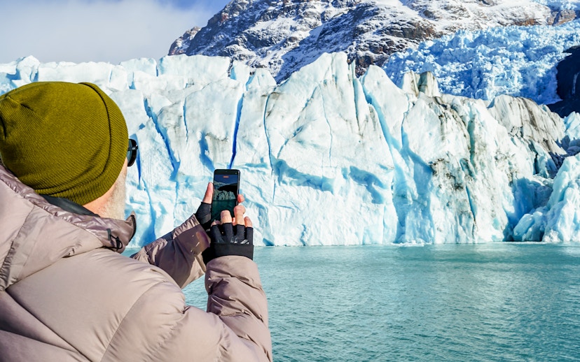 Tourist photographing Perito Moreno Glacier from a cruise boat in Argentina.