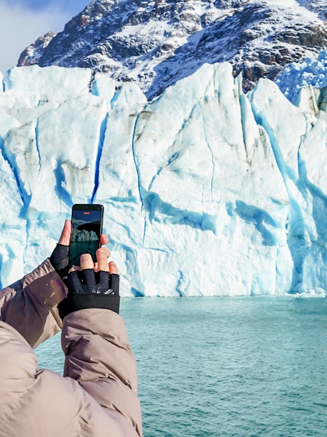 Tourist photographing Perito Moreno Glacier from a cruise boat in Argentina.