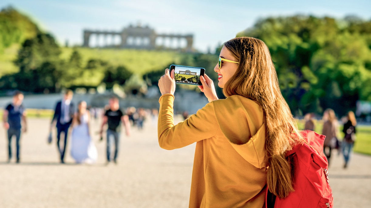 Visitor photographing Schönbrunn Palace gardens in Vienna.