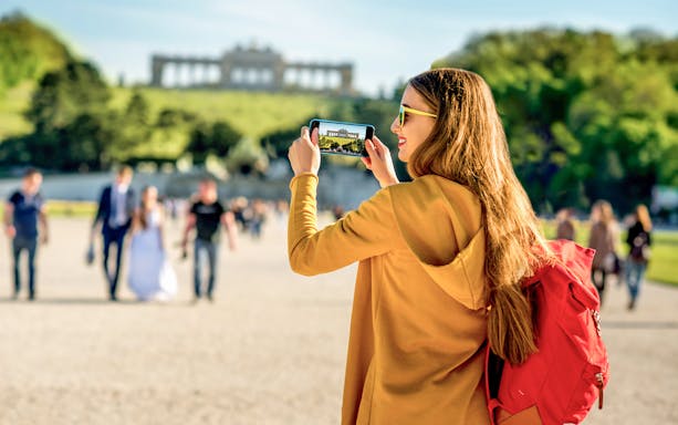 Visitor photographing Schönbrunn Palace gardens in Vienna.