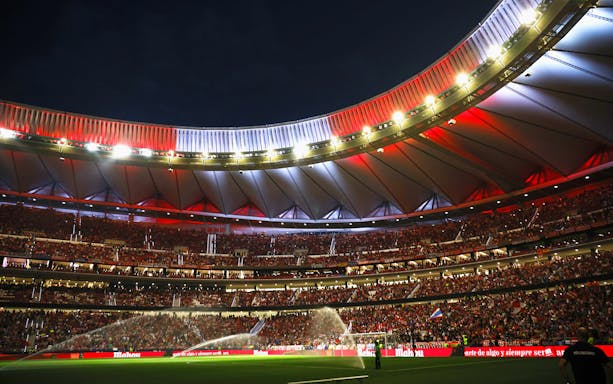 Wanda Metropolitano Stadium in Madrid, Spain, illuminated at night during a football match.