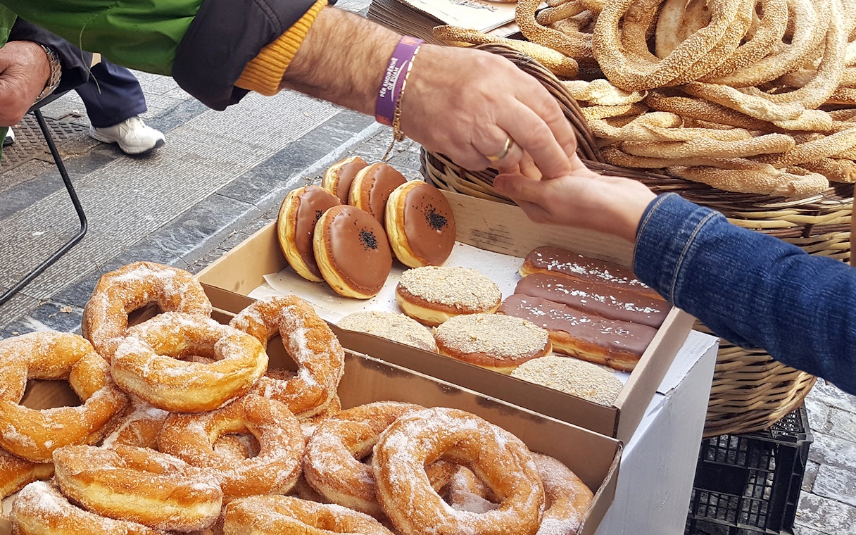 Street vendor exchanging Greek pastries during Athens food tour.