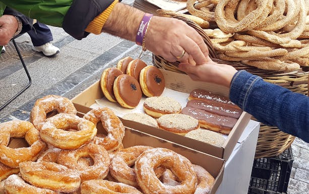 Street vendor exchanging Greek pastries during Athens food tour.