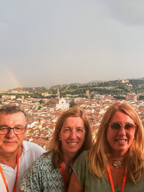 Group enjoying view from Brunelleschi’s Dome in Florence, Italy, with cityscape and rainbow in background.