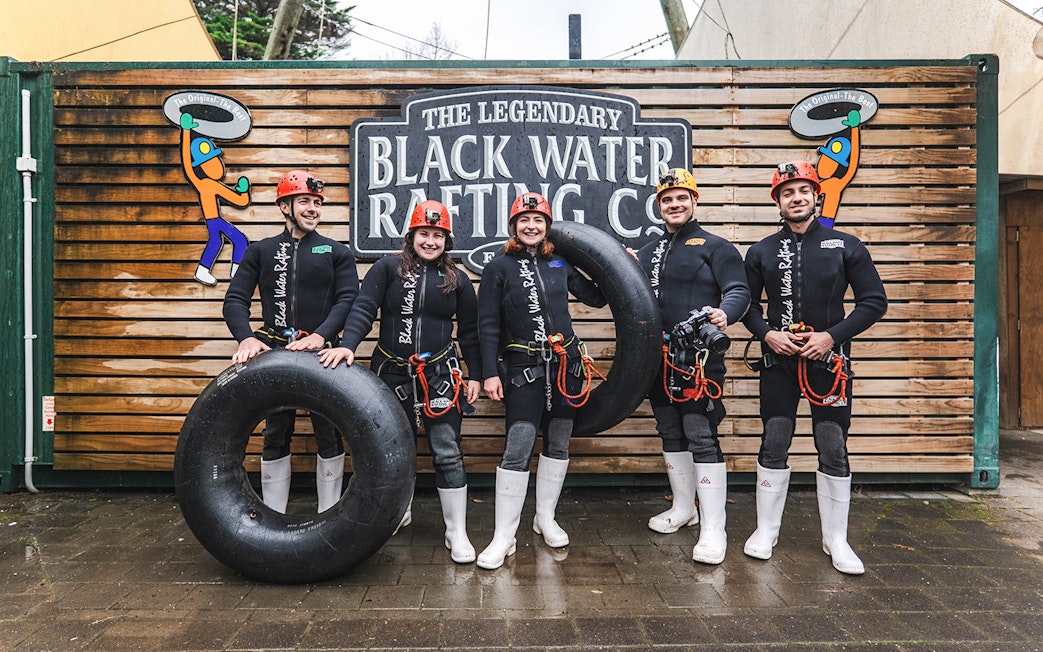 Group of people in wetsuits with inner tubes at Black Water Rafting, Waitomo.