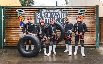 Group of people in wetsuits with inner tubes at Black Water Rafting, Waitomo.