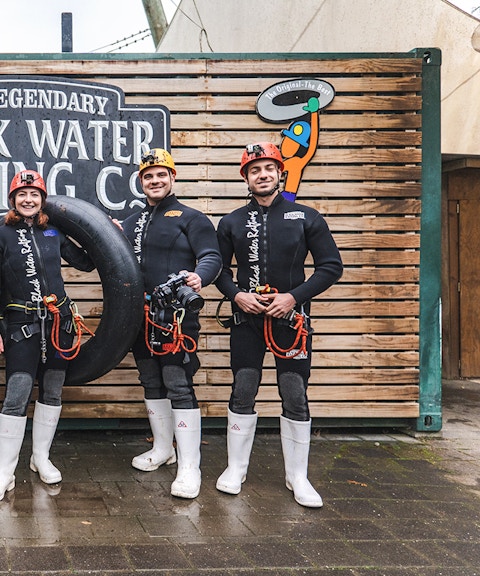 Group of people in wetsuits with inner tubes at Black Water Rafting, Waitomo.