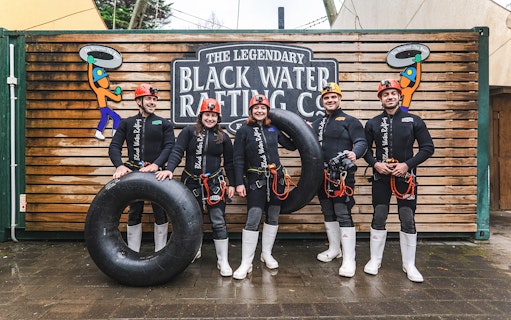 Group of people in wetsuits with inner tubes at Black Water Rafting, Waitomo.