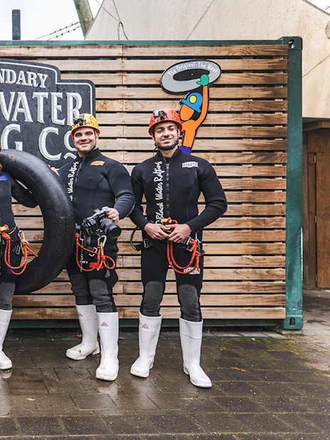 Group of people in wetsuits with inner tubes at Black Water Rafting, Waitomo.