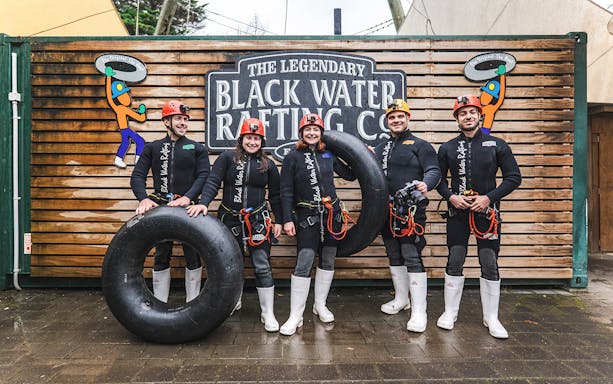 Group of people in wetsuits with inner tubes at Black Water Rafting, Waitomo.