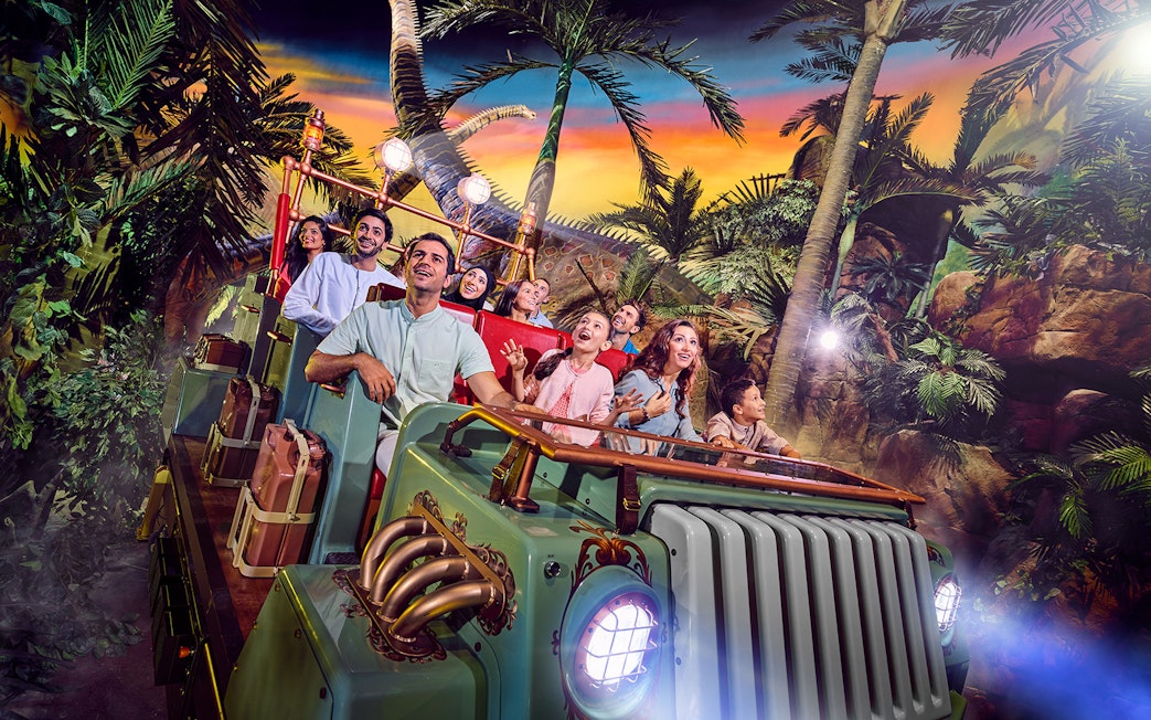 Group enjoying a theme park ride surrounded by tropical scenery in Dubai.