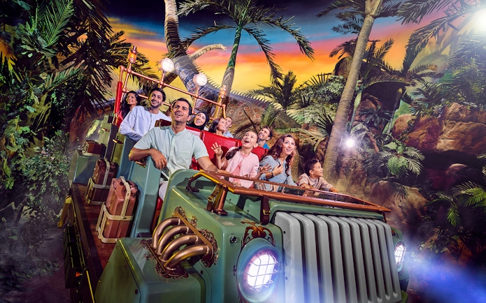 Group enjoying a theme park ride surrounded by tropical scenery in Dubai.