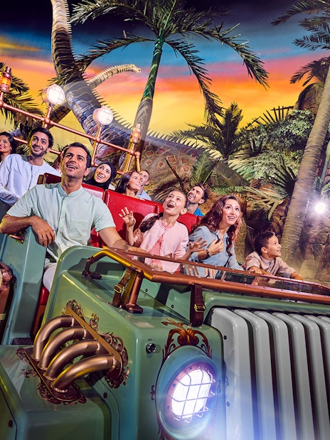 Group enjoying a theme park ride surrounded by tropical scenery in Dubai.